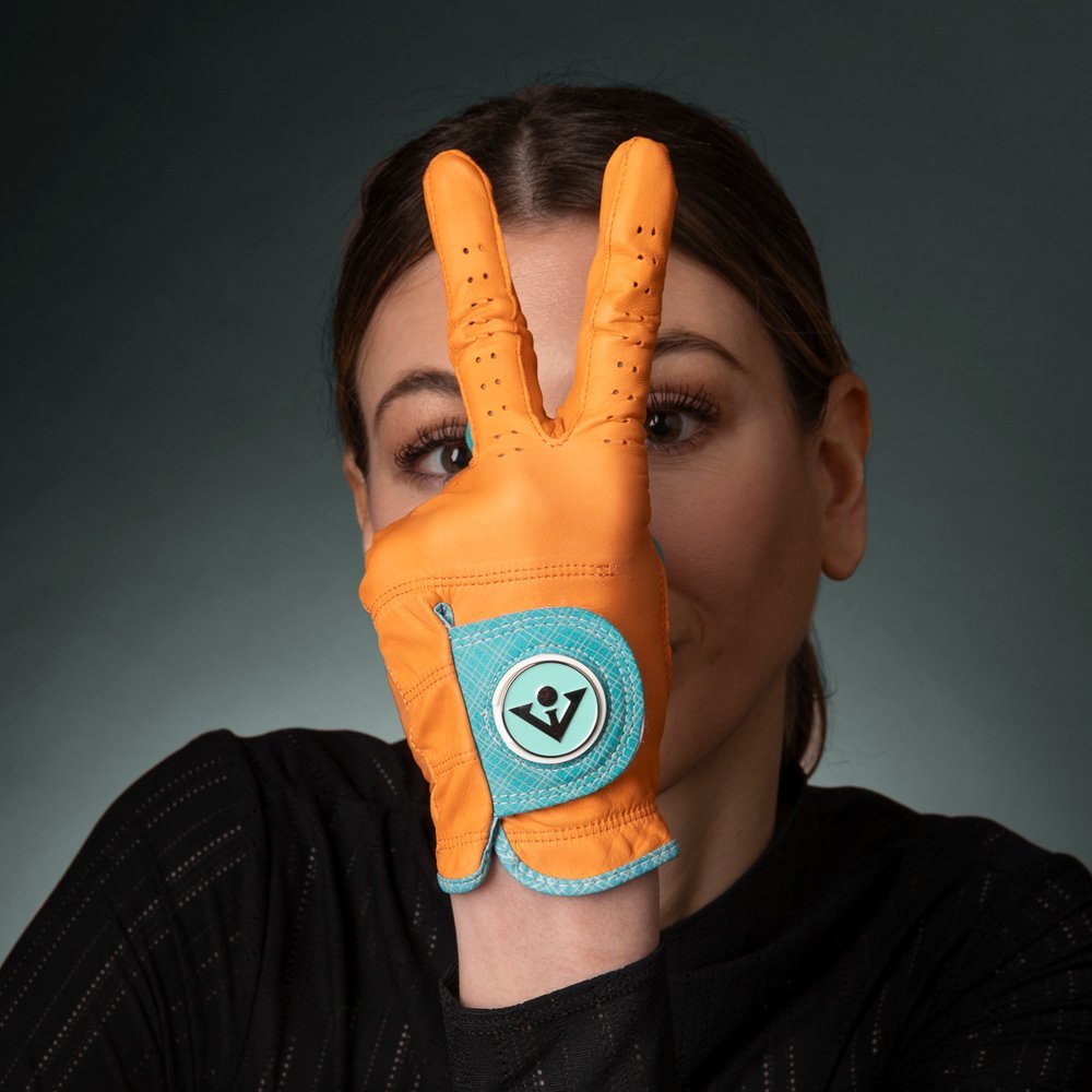 Woman in VivanTee orange golf glove holding up piece sign, showing the bright orange and blue accents.