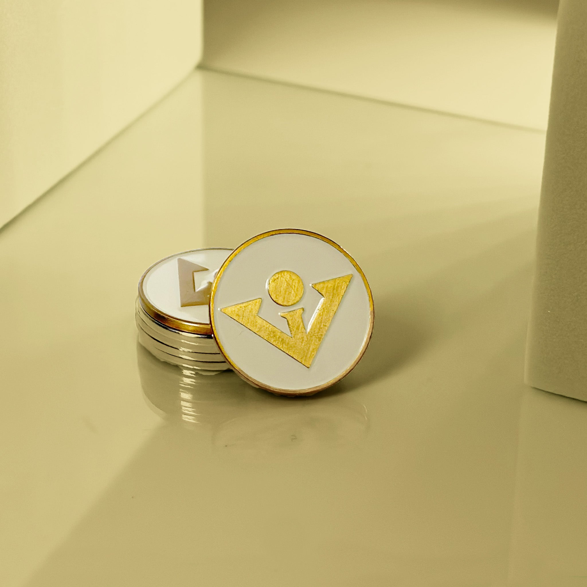 Cream and copper magnetic golf ball marker, with a gold colored light in the backdrop to show case it's unique details.